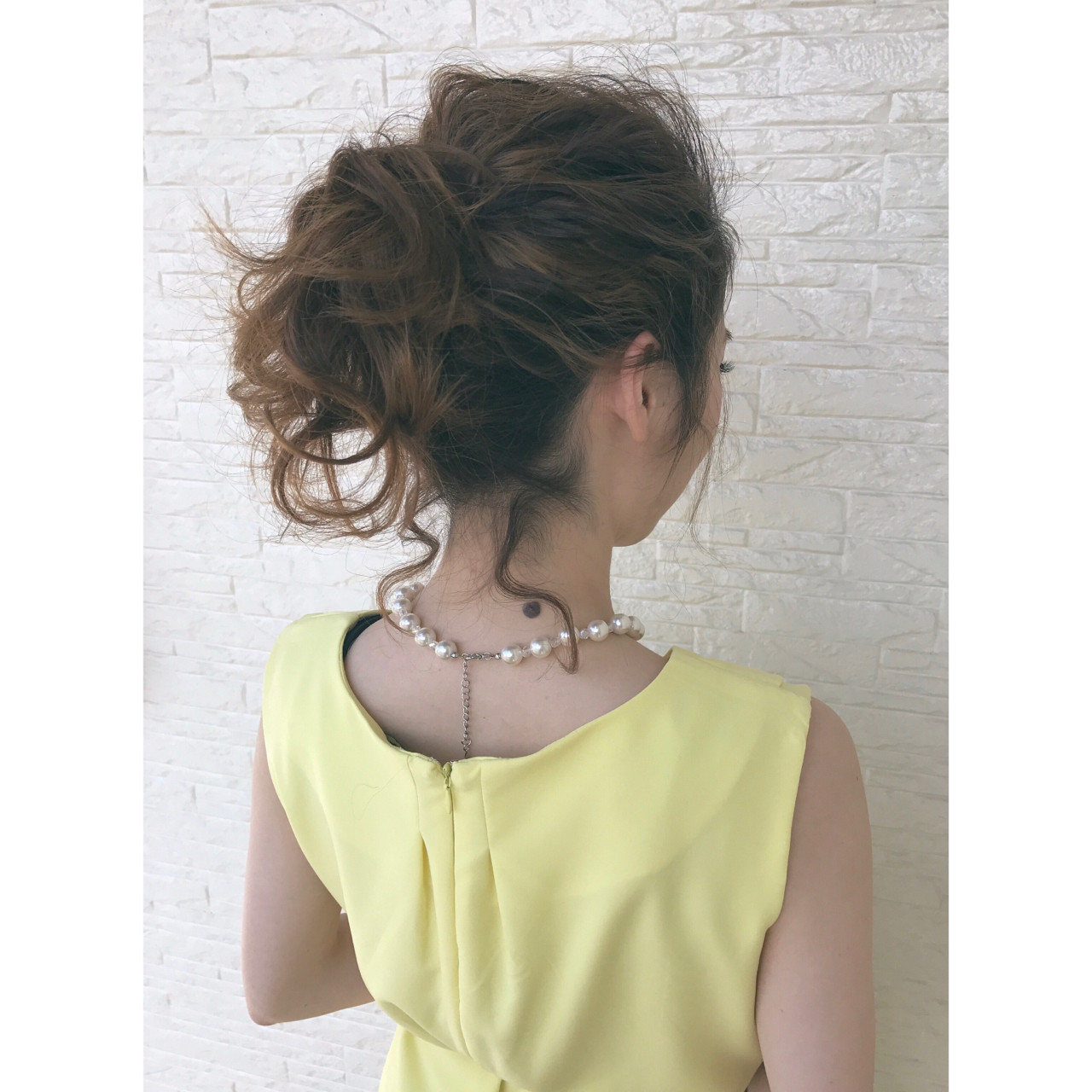 中間の位置で、カールヘアをルーズに結ばれています。一見シニヨン風でもあり、後れ毛も可愛いアレンジになっています！